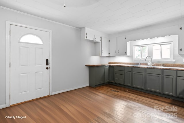 kitchen featuring gray cabinetry, ornamental molding, dark wood-style floors, and a sink