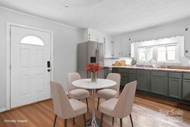 kitchen featuring wood finished floors, stainless steel fridge with ice dispenser, ornamental molding, and a sink