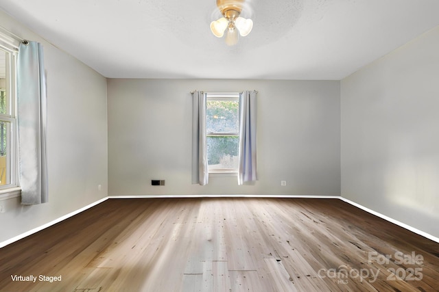 empty room with baseboards, wood finished floors, and ceiling fan