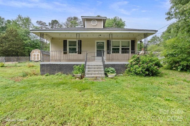 bungalow-style house with covered porch, stairway, fence, an outbuilding, and a storage shed