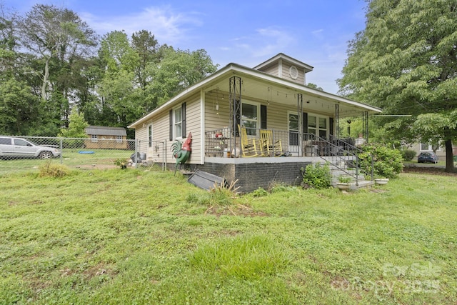 bungalow with covered porch, fence, and a front lawn