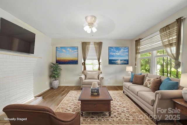 living room with a ceiling fan, wood finished floors, and baseboards