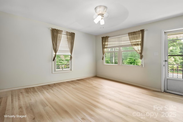 spare room with baseboards, ceiling fan, and light wood finished floors