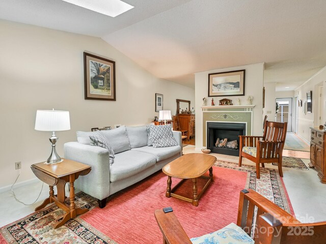 living area with a fireplace with raised hearth and vaulted ceiling with skylight