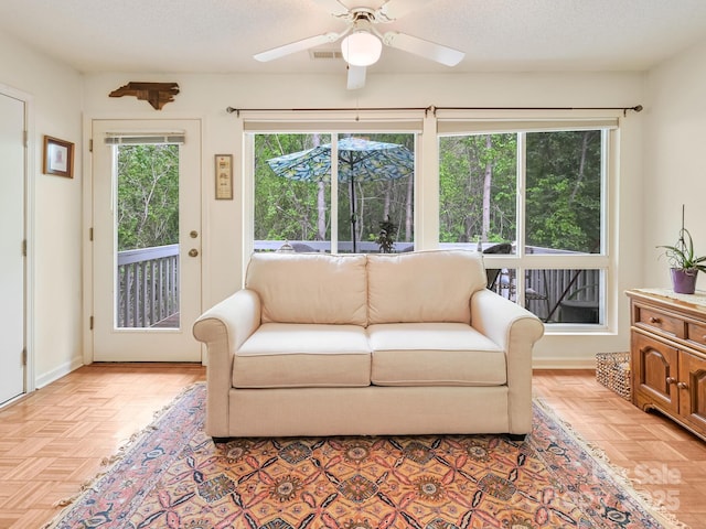 living area featuring ceiling fan and a textured ceiling