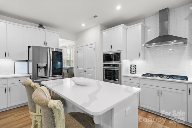1287 Fishing Creek Rd, Lake Wylie, SC 29710 - kitchen featuring wall chimney range hood, appliances with stainless steel finishes, backsplash, light countertops, and light wood-type flooring
