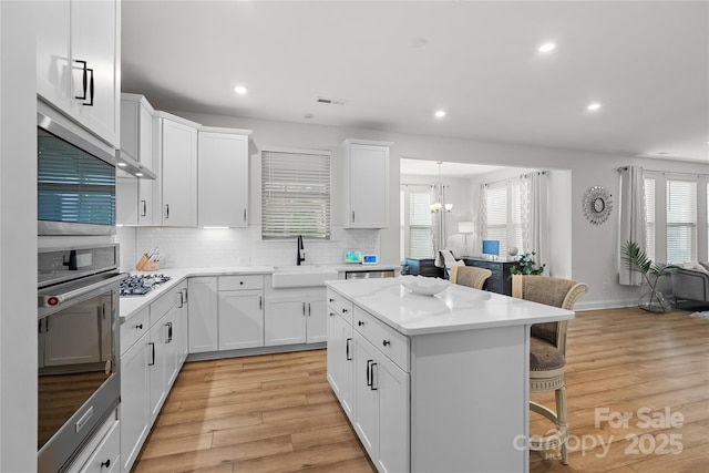 1287 Fishing Creek Rd, Lake Wylie, SC 29710 - kitchen with a breakfast bar area, a sink, light wood-style flooring, backsplash, and a center island