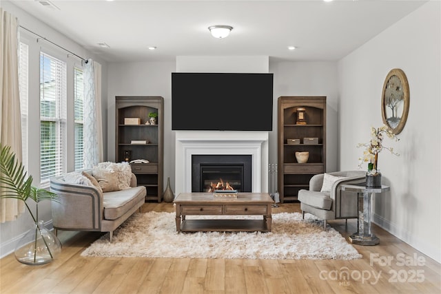1287 Fishing Creek Rd, Lake Wylie, SC 29710 - living area featuring wood finished floors, baseboards, a glass covered fireplace, and recessed lighting