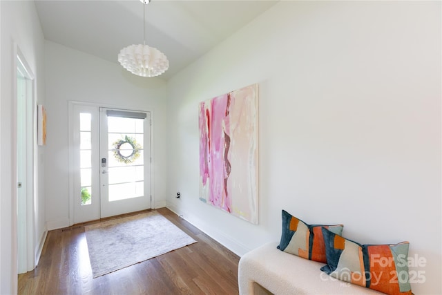 foyer entrance featuring baseboards, a chandelier, and wood finished floors