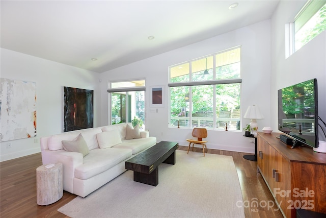 living area featuring baseboards, vaulted ceiling, and dark wood-style floors