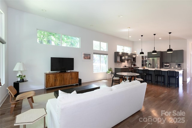 living area with baseboards, dark wood-type flooring, recessed lighting, and a towering ceiling