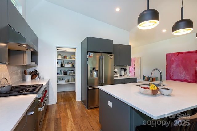 kitchen featuring wood finished floors, modern cabinets, light countertops, a sink, and premium appliances