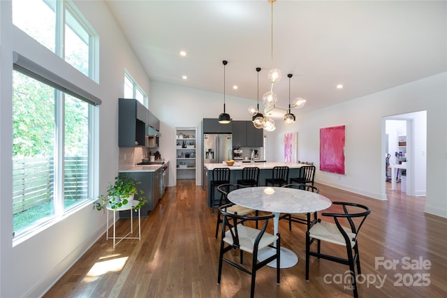 dining space with plenty of natural light, recessed lighting, dark wood-type flooring, and a high ceiling