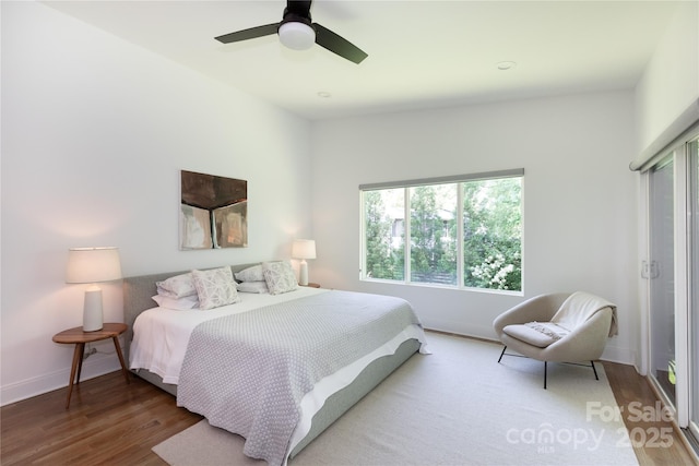 bedroom with baseboards, a ceiling fan, wood finished floors, and multiple windows