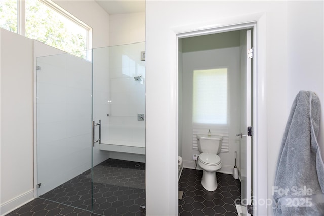 bathroom featuring baseboards, toilet, and a shower stall