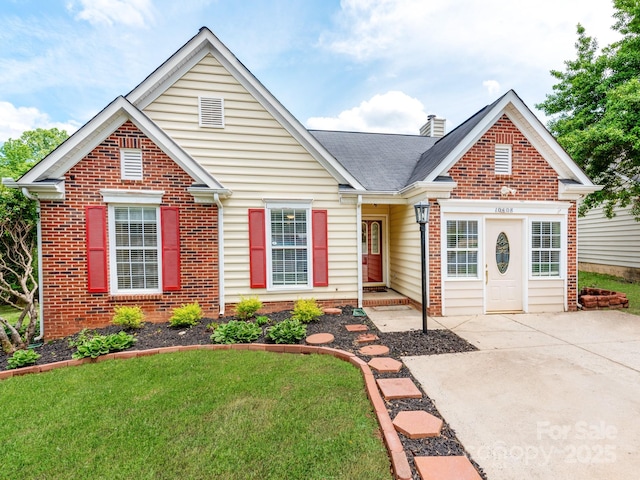 traditional-style home featuring brick siding, a chimney, a front lawn, and a shingled roof