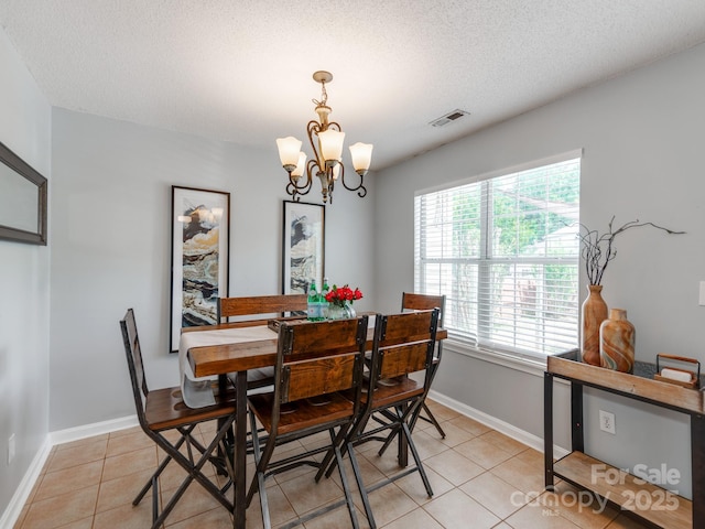dining area with a chandelier, light tile patterned flooring, baseboards, and a textured ceiling