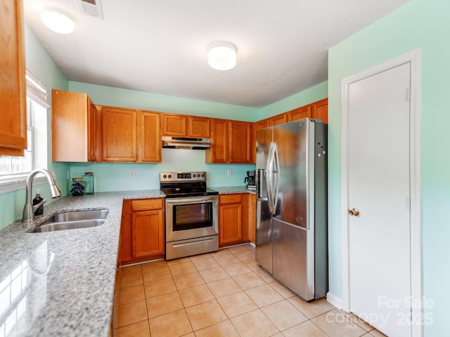 kitchen with appliances with stainless steel finishes, a sink, under cabinet range hood, and light tile patterned floors