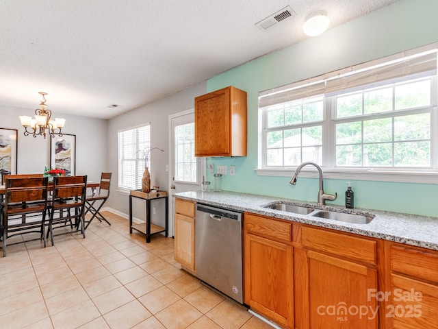 kitchen with stainless steel dishwasher, a sink, healthy amount of natural light, light tile patterned floors, and a textured ceiling