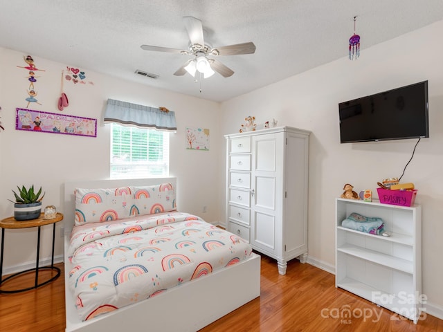 bedroom with light wood finished floors, a ceiling fan, and a textured ceiling