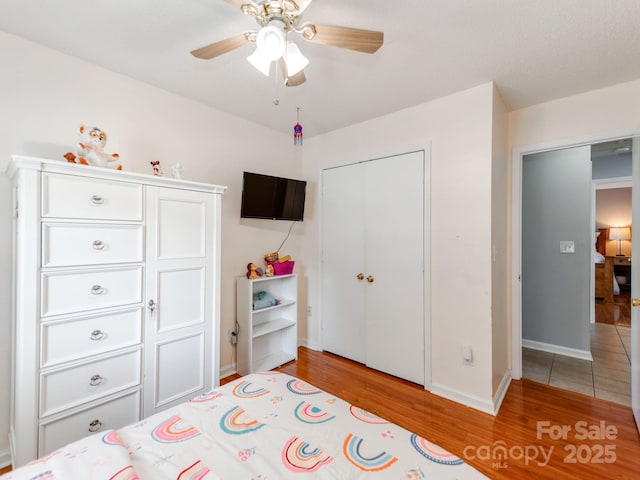 bedroom featuring light wood-style floors, baseboards, a closet, and a ceiling fan