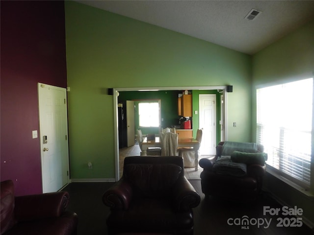living area with carpet, visible vents, baseboards, and high vaulted ceiling