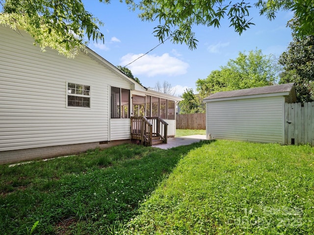 view of yard featuring an outdoor structure, a sunroom, and fence