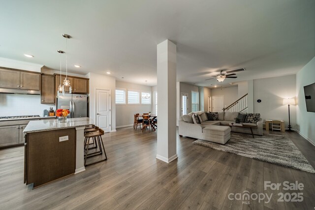 804 Lyndon Station Dr, Pineville, NC 28134 - kitchen featuring under cabinet range hood, stainless steel refrigerator with ice dispenser, baseboards, and dark wood-type flooring