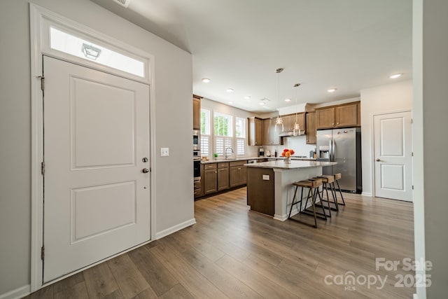 804 Lyndon Station Dr, Pineville, NC 28134 - kitchen with a kitchen breakfast bar, a kitchen island, appliances with stainless steel finishes, brown cabinets, and a sink