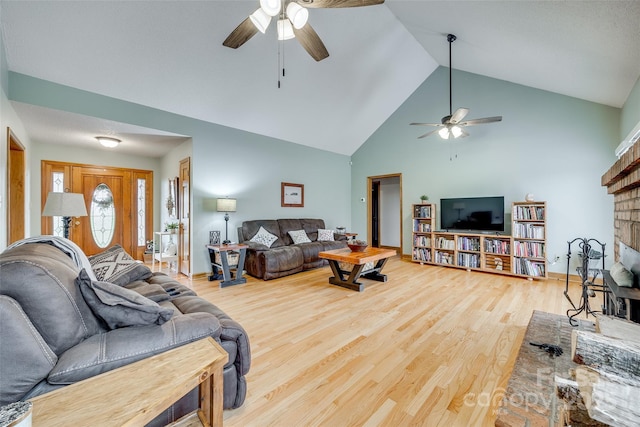 living area featuring high vaulted ceiling, wood finished floors, ceiling fan, and a brick fireplace