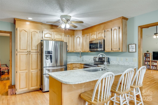 kitchen with a textured ceiling, ceiling fan, stainless steel appliances, and a peninsula