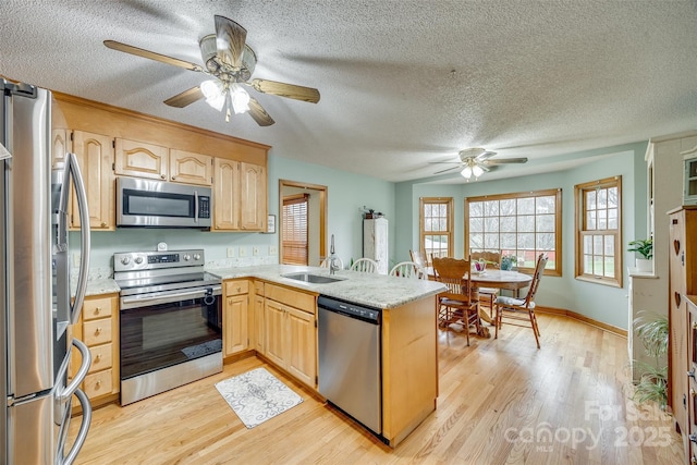 kitchen featuring a peninsula, light wood-style flooring, appliances with stainless steel finishes, ceiling fan, and a textured ceiling