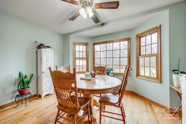 dining area with baseboards, light wood-type flooring, ceiling fan, and a textured ceiling