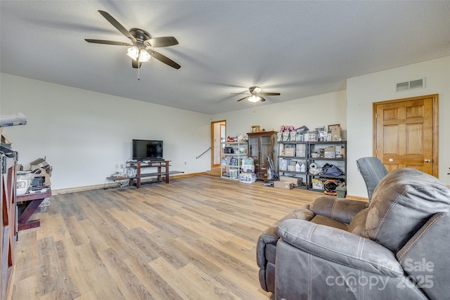 living area with visible vents, ceiling fan, a textured ceiling, and light wood-style flooring
