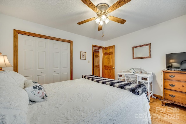 bedroom with a closet, a ceiling fan, light wood-style flooring, baseboards, and a textured ceiling