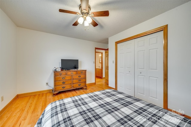 bedroom with light wood-style flooring, a closet, ceiling fan, baseboards, and a textured ceiling