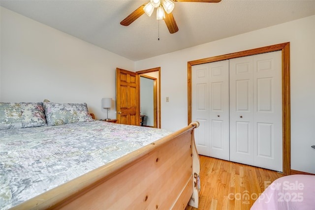 bedroom with a ceiling fan, light wood-style flooring, and a closet