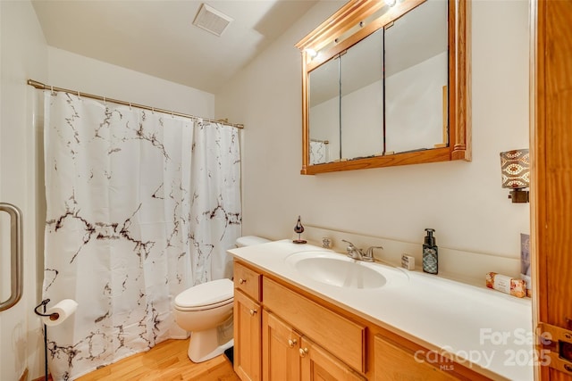 bathroom featuring curtained shower, visible vents, toilet, wood finished floors, and vanity