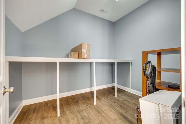 unfurnished office with visible vents, baseboards, lofted ceiling, and wood finished floors
