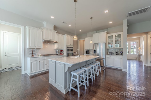 kitchen featuring tasteful backsplash, under cabinet range hood, appliances with stainless steel finishes, white cabinets, and visible vents