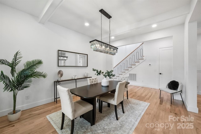 dining room featuring stairway, visible vents, light wood-type flooring, and beamed ceiling