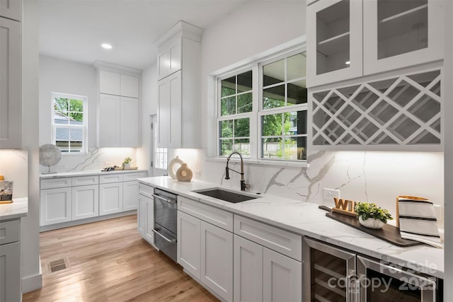 kitchen featuring tasteful backsplash, a wealth of natural light, dishwasher, a sink, and wine cooler