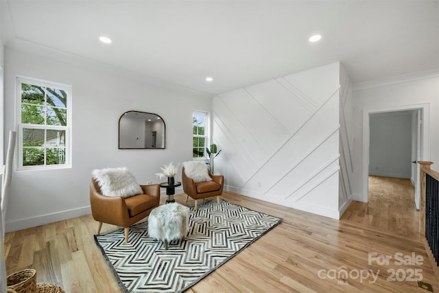 sitting room with a healthy amount of sunlight, crown molding, and light wood finished floors