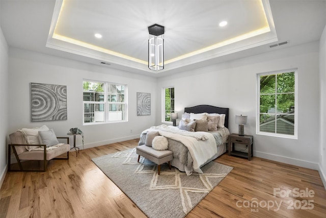 bedroom featuring a raised ceiling, visible vents, baseboards, recessed lighting, and light wood finished floors