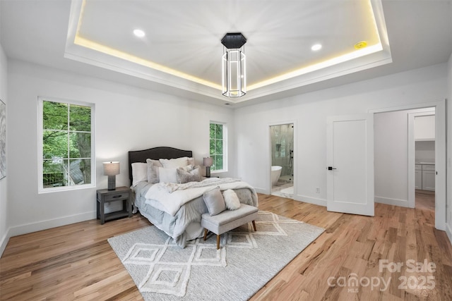bedroom featuring recessed lighting, connected bathroom, light wood-style floors, a tray ceiling, and baseboards