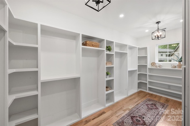 walk in closet featuring wood finished floors and a chandelier