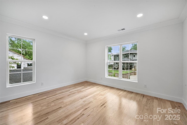 unfurnished room with baseboards, a healthy amount of sunlight, light wood finished floors, and crown molding