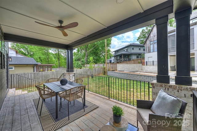 deck with outdoor dining area, a yard, a ceiling fan, and a fenced backyard