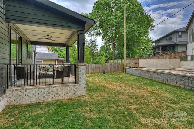 view of yard featuring covered porch, ceiling fan, and a fenced backyard