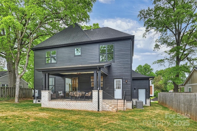 rear view of property with a fenced backyard, a shingled roof, a yard, and a patio area